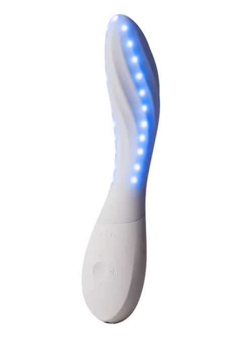 A white curved personal massager with a wavy surface and a row of glowing blue LED lights, shown against a plain white background.